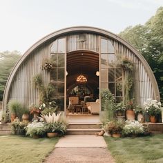 a large metal building sitting on top of a lush green field with lots of plants