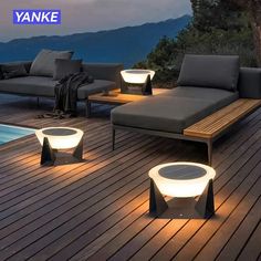 an outdoor lounge area with lights on the floor and in the background is a swimming pool