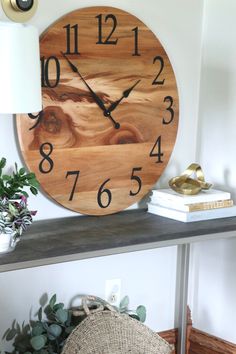 a wooden clock sitting on top of a shelf next to a lamp and potted plant