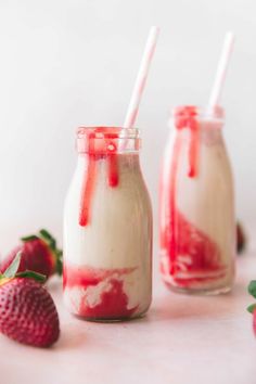 two jars filled with yogurt and strawberries next to each other on a table