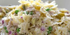 a close up view of a pasta salad with peas and other toppings on a white plate