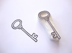 a metal key sitting on top of a piece of paper next to a rubber stamp