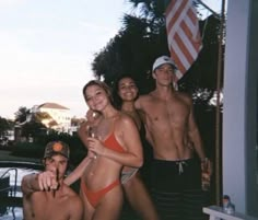 a group of people standing next to each other in front of a pool with an american flag