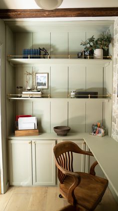 a desk and chair in a room with white walls, shelves and wood flooring