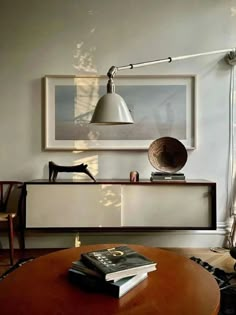 a living room with a table, chair and lamp on it's sideboard