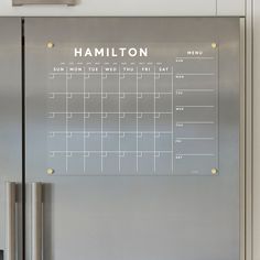 a stainless steel refrigerator with a magnetic calendar on the front and side panels that says,'hamilton '