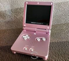 a pink portable game system sitting on top of a couch