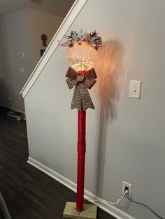 a lighted christmas decoration on top of a red pole in the corner of a room