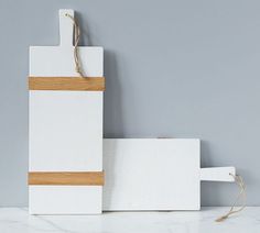 two white cutting boards with wooden handles on a table