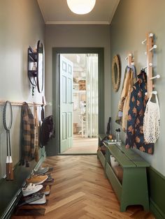 a hallway with green benches and coat racks on the wall, along with wooden flooring