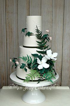 a three tiered cake with white flowers and greenery