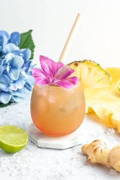 a drink in a glass with a pink flower on the rim next to sliced pineapples