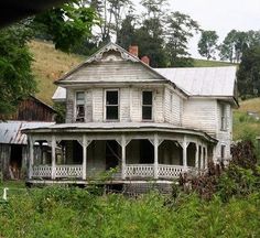 an old house sitting on top of a lush green hillside