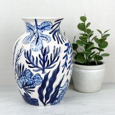 a blue and white vase sitting next to a potted plant