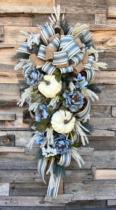 a wreath with blue and white flowers hanging on a wooden wall