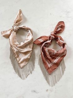 two scarves with tassels on them sitting on a white counter top next to each other