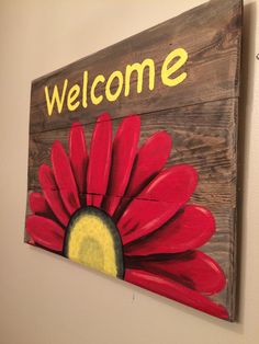 a wooden sign that says welcome with a red flower painted on the front and yellow center