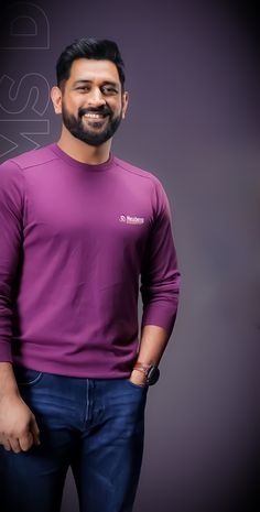 a man in a purple shirt standing with his hands on his hips and smiling at the camera