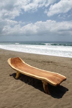 a wooden bench sitting on top of a sandy beach next to the ocean and waves