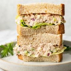 two sandwiches stacked on top of each other with lettuce and tuna in the middle