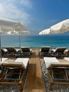 lounge chairs and umbrellas are set up on the beach