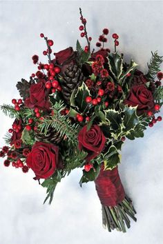 a bouquet of red roses and greenery with pine cones on the top is shown