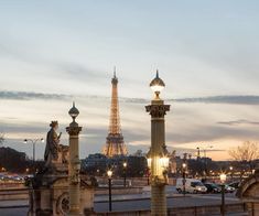 the eiffel tower is lit up at night in front of some statues and buildings