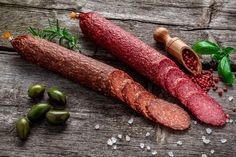 three different types of sausages on a wooden table next to peppers and peppercorst