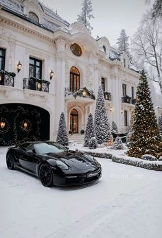 a black sports car parked in front of a large white house with christmas trees and lights