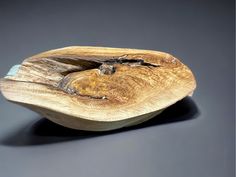 a wooden bowl sitting on top of a black table next to a gray wall and floor