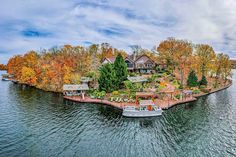 an island in the middle of a lake surrounded by trees and houses with boats on it