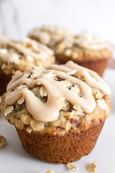 there are muffins with icing on top of each and some nuts around them