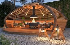 a wooden gazebo sitting on top of a stone floor next to a table and chairs