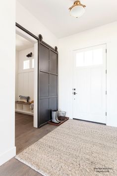 an empty room with two doors and a rug on the floor in front of it