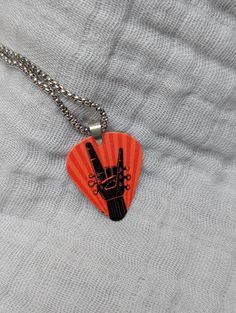 an orange guitar picker with a peace sign painted on it's side hanging from a chain