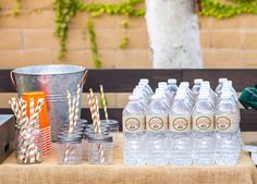 a table topped with bottles of water and paper straws