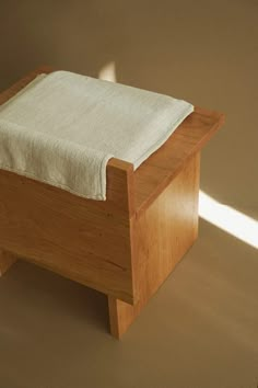 a small wooden bed with a white blanket on it