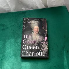 the good queen charlotte book is sitting on a green table