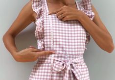 a woman in a pink and white checkered dress holding her hands on her hip