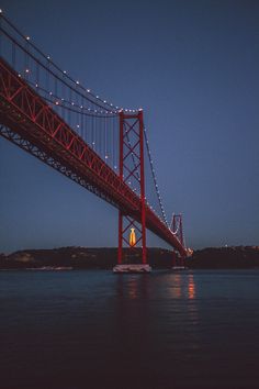 a large red bridge over water at night