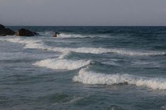 two surfers are riding the waves on their surfboards in the ocean near some rocks