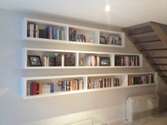 the bookshelves are lined up against the wall in this living room with stairs