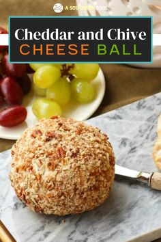 a cheese ball sitting on top of a marble cutting board next to grapes and bread