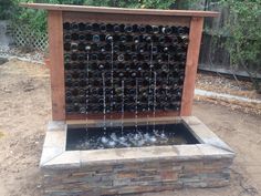 a fountain made out of wine bottles in the middle of a yard with water flowing from it