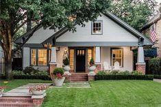 a house that is sitting in the grass with flowers on it's front lawn