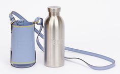 a silver water bottle next to a light blue bag on a white background with a strap