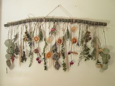 a wall hanging made out of branches with flowers and other things on the top of it