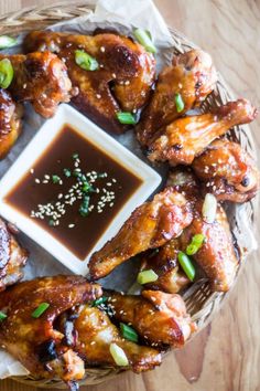 chicken wings with dipping sauce in a wicker basket on top of a wooden table