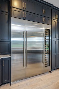 a stainless steel double door refrigerator in a kitchen with wooden floors and black cabinetry