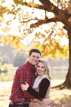 a man and woman hugging in front of a tree